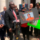 Attorney Benjamin Crump, foreground left, and Doreen Coleman, mother of Randy Cox, hold a poster of Cox, outside a courthouse in New Haven, Conn., Friday, July 8, 2022. Cox, who was being transported in a police van without seatbelts, was paralyzed when the van braked suddenly. His family asked federal authorities Friday to file civil rights charges against the officers involved.